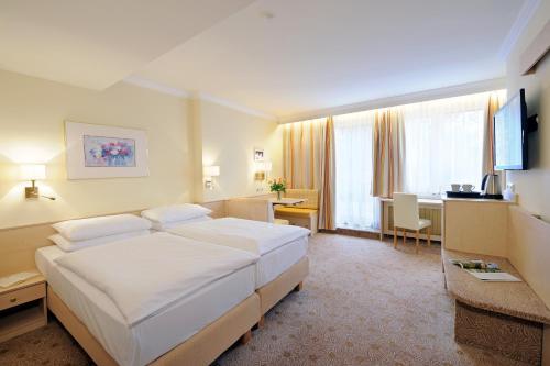 a hotel room with a large bed and a desk at Hotel Scherer in Salzburg