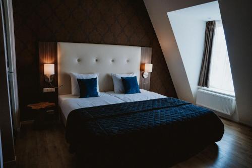 a bedroom with a large bed with blue pillows at Hotel Brasserie Florian in Wijk bij Duurstede
