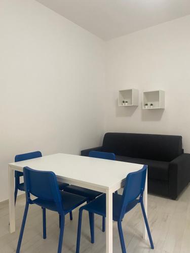 une table blanche avec des chaises bleues et un canapé dans l'établissement Oltremare Case Vacanza, mini appartamenti, à Diamante