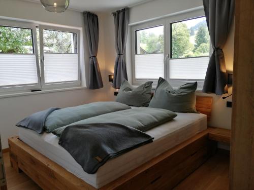 a bed in a bedroom with three windows at Das Prinzenberg Appartement in Maria Alm am Steinernen Meer