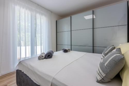 a bedroom with a large white bed with a large window at Villa Una in Krk