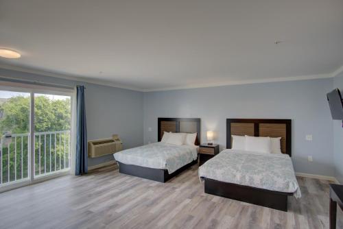 a hotel room with two beds and a balcony at Dhimas Bayview Suites in Ocean City