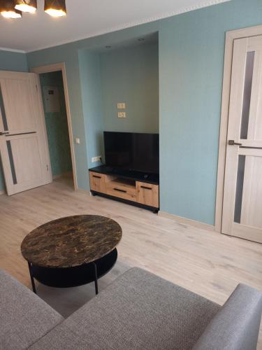 a living room with a table and a flat screen tv at Kandavas Street City Center Apartment in Daugavpils