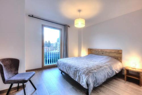 a bedroom with a bed and a chair and a window at Appartement 60M2 - TELECABINE SAINT GERVAIS - 201 in Saint-Gervais-les-Bains