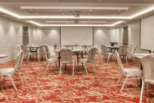 a conference room with tables and chairs and a projection screen at Geneva Hotel in Amman