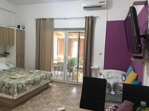 um quarto com uma cama, uma televisão e uma varanda em Botic Apartments em Šilo