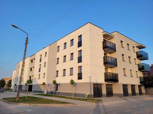 a white building with palm trees in front of it at Apartament Olecko Centrum in Olecko