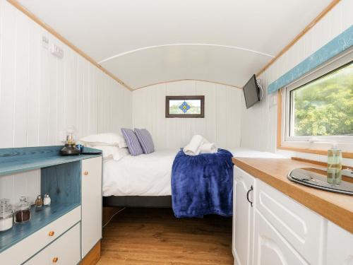 a small bedroom with a bed and a window at Shepherds Hut in Lostwithiel