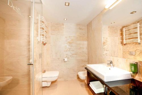 a bathroom with a sink and a toilet and a shower at Hotel DeSilva Premium Opole in Opole