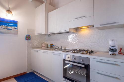 a kitchen with white cabinets and a stove top oven at Happy Guest Apartments - Blue Lake Therapy in Riva di Solto