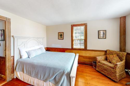 a bedroom with a bed and a chair at Beautiful Oceanside House in Falmouth