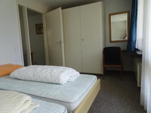 ein Schlafzimmer mit zwei Betten, einem Schrank und einem Stuhl in der Unterkunft Fortuna 307 in Leukerbad