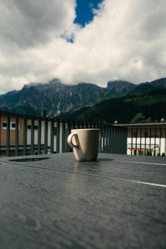 a coffee cup sitting on a table with mountains in the background at Wia dahoam in Leogang