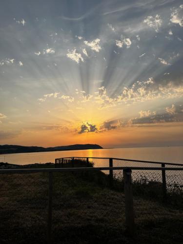 a sunset over a body of water with a fence at Anchor's Drop in Blue Anchor