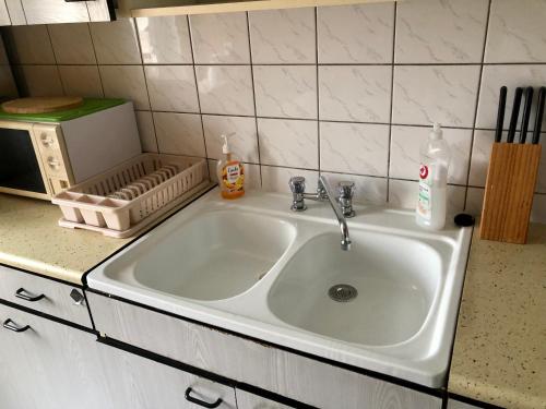 a white sink in a kitchen next to a microwave at Słoneczny Apartament 3 - oddzielne pokoje Centrum Jarot in Olsztyn