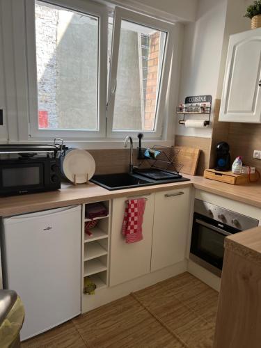 une cuisine avec des armoires blanches, un évier et un micro-ondes dans l'établissement Le dunkerquois proximité du centre ville et de la plage, à Dunkerque