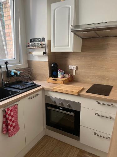 une cuisine avec des armoires blanches et un four à plaques de cuisson dans l'établissement Le dunkerquois proximité du centre ville et de la plage, à Dunkerque