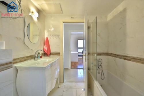 Sea view family relax apartment في نتانيا: حمام مع حوض ومغسلة ودش
