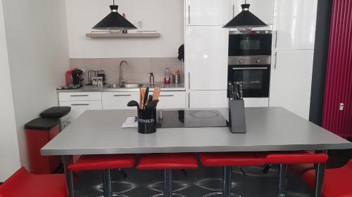 une cuisine avec un comptoir blanc et des chaises rouges dans l'établissement LOFT 100m2, à Toulon