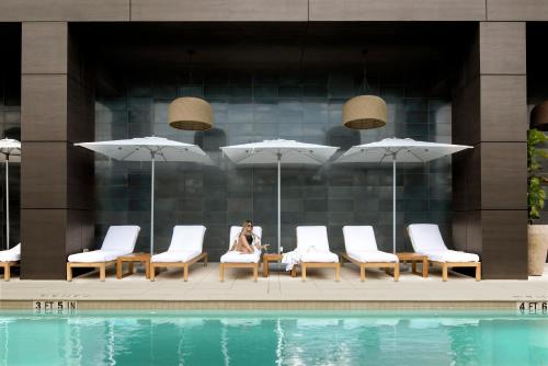 ette luxury hotel & spa في أورلاندو: امرأة جالسة على كرسي بجوار حمام السباحة