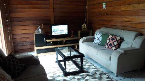 a living room with two couches and a tv at Sitio Santa Lucia in Santa Teresa