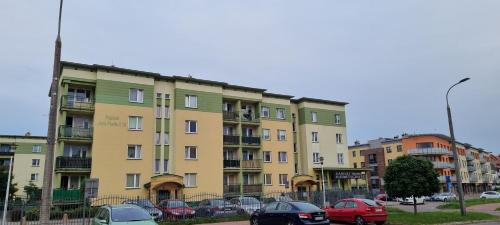 a yellow building with cars parked in a parking lot at Przytulny - blisko centrum in Suwałki