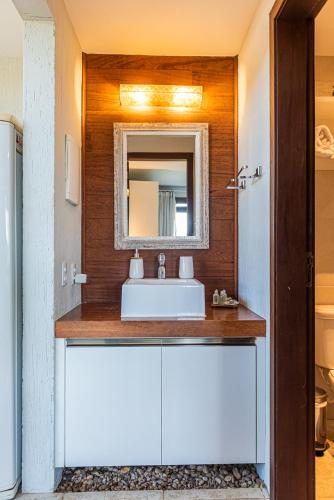 a bathroom with a white sink and a mirror at Morada Prainha in Garopaba