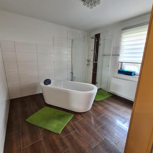 a bathroom with a white tub and two green rugs at Ferienwohnung Claudia in Altossiach