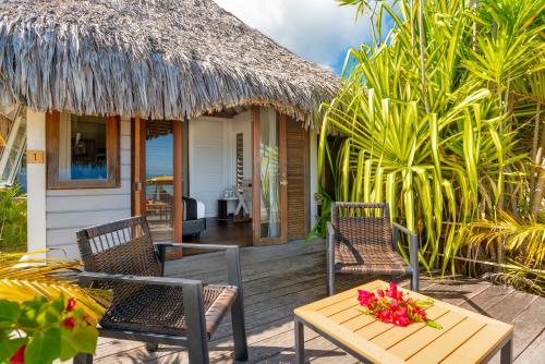 a wooden deck with chairs and a table with flowers at Moorea Beach Lodge in Moorea