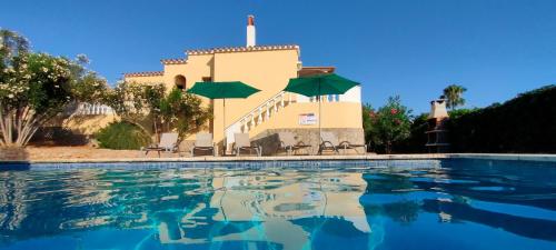 a pool with chairs and umbrellas in front of a building at Casa MALIBU in Son Bou