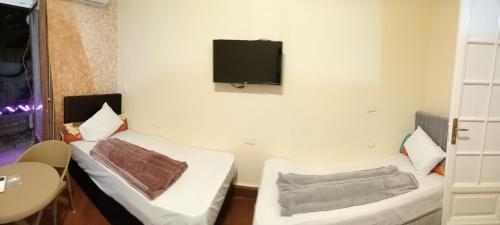 a room with two beds and a tv on the wall at New One Hotel in Cairo