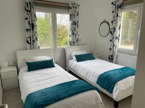 two beds in a room with two windows at Villa Ambios in Peyia