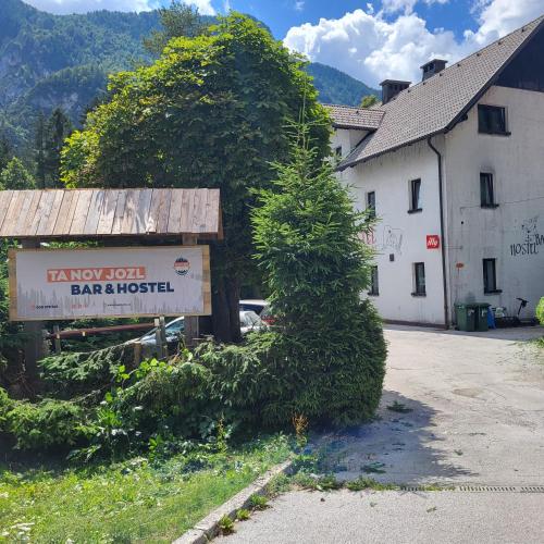 a sign in front of a building with a tree at Hostel pr Tanovmu Jozlnu in Mojstrana