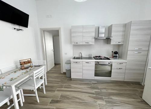 a kitchen with white cabinets and a sink and a table at in Via Margherita in Santa Maria di Castellabate