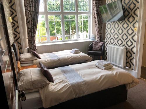 two beds in a room with a window at Braehead Guest House in Inverness