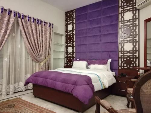 Dormitorio púrpura con cama y pared púrpura en Hotel island Clifton, en Karachi