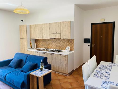 een woonkamer met een blauwe bank en een keuken bij Marina Apartament in Scalea