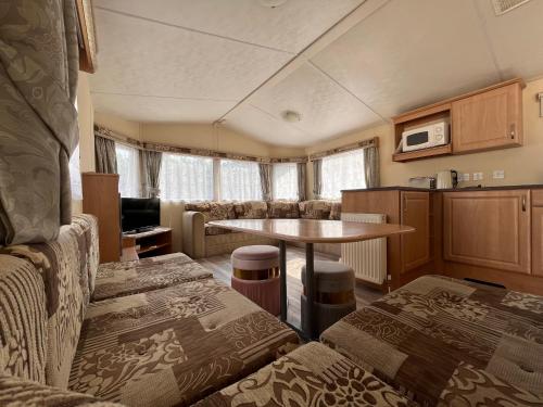 a living room with a table and a kitchen at Contemporary Caravan at Newquay Holiday Park in Newquay