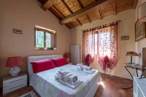 Un dormitorio con una cama con almohadas rojas y una ventana en Santa Croce Resort, en Torgiano