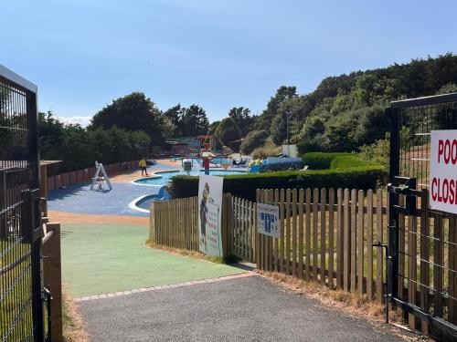 a fence in front of a park with a playground at Contemporary Caravan at Newquay Holiday Park in Newquay