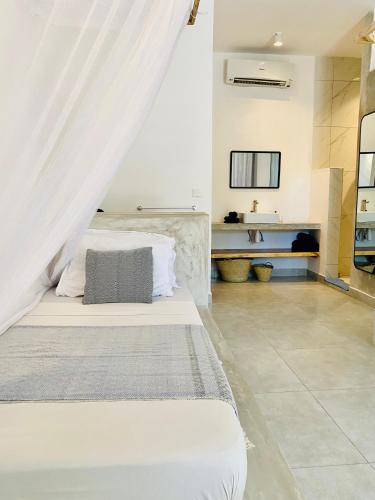 a bedroom with a white bed with a canopy at Badolina Bungalows in Nungwi