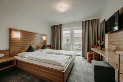 a hotel room with a bed and a television at Hotel VIEW - incl Joker Card in Summer in Saalbach Hinterglemm