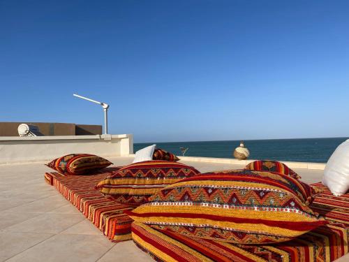 a pile of blankets and pillows sitting on a patio with the ocean at Paradisiac and luxurious villa with private beach in Dakhla in Dakhla