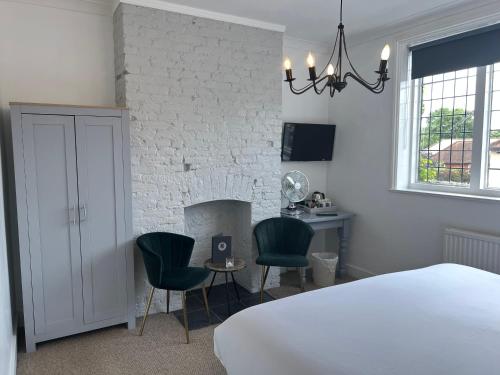 a bedroom with a bed and chairs and a fireplace at Castle Hotel in Eynsford