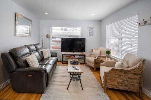 a living room with a leather couch and a flat screen tv at Sugar House Urban Basecamp in Salt Lake City