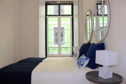 um quarto com uma cama com um espelho e uma janela em Lisbon Coral Apartment em Lisboa
