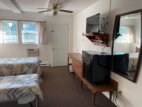 a room with a television and a desk with a mirror at Norfolk Motel in Fredericton