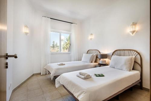 two beds in a room with white walls and a window at Modern and Spacious Two Bedroom Apartment in Carvoeiro