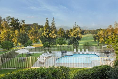 a swimming pool with chairs and a golf course at Ayres Suites Diamond Bar in Diamond Bar