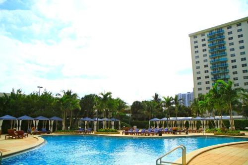 a large swimming pool with chairs and umbrellas at Sunny Isles Ocean Reserve Condo Apartments in Miami Beach